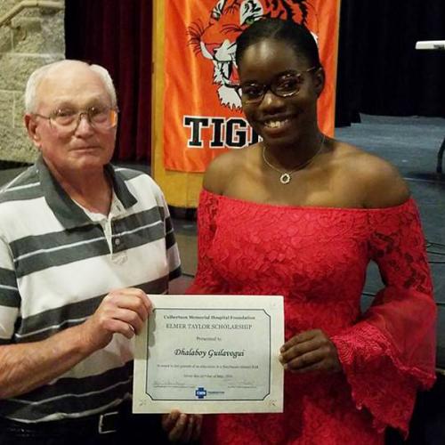 An older gentleman giving a scholarship to a young woman