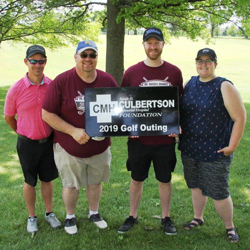 A group of people standing next to eachother holding a Culbertson Memorial Hospital Sign