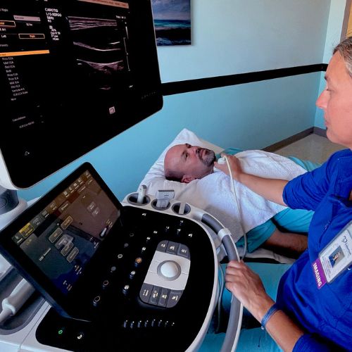 Imaging Technician using an ultrasound machine to see the veins in a patients neck